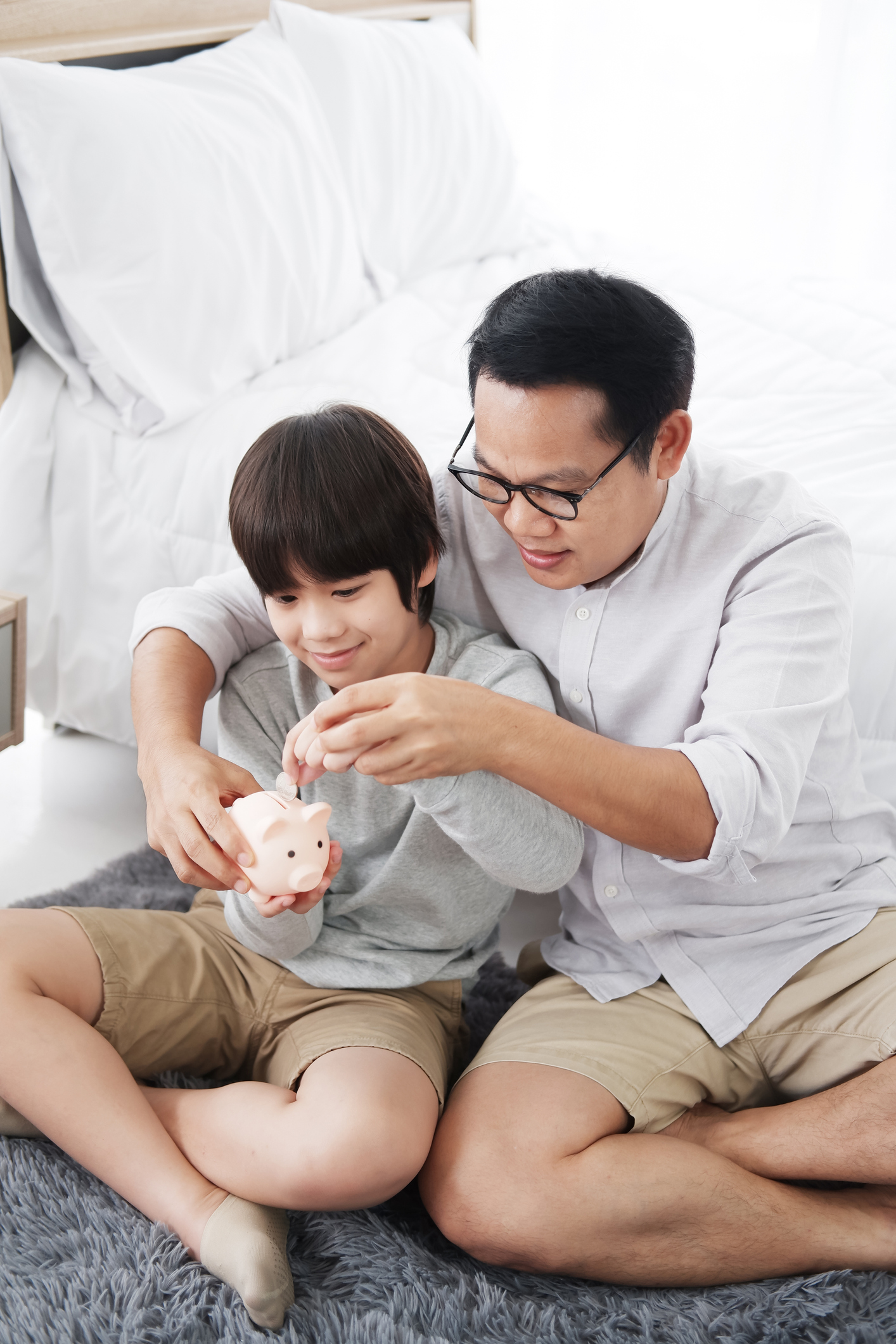 Smiling Asian little son child is putting coins into piggy bank - Whole Life Insurance | Weinstein Wealth